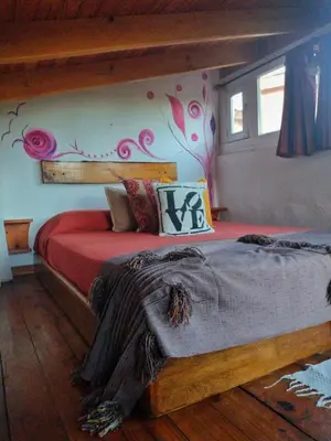 a bedroom with a bed with red sheets and flowers on the wall at Del Sol a la Montaña EcoLodge - Turismo Consciente in Potrero de Garay