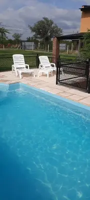 two white chairs sitting next to a swimming pool at Dulce Refugio in Cortaderas