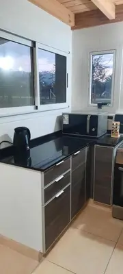 a kitchen with a black counter top and two windows at Dulce Refugio in Cortaderas