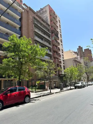 a red car parked on the side of a city street at Departamento premium, la mejor zona de Nueva Córdoba in Cordoba