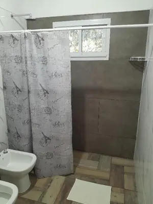 a bathroom with a shower curtain and a toilet at Chalet El Buho in Villa General Belgrano