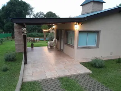 a patio with awning next to a house at Chalet El Buho in Villa General Belgrano