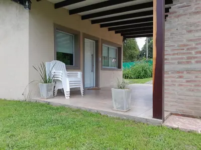 a patio with two white chairs on a house at Chalet El Buho in Villa General Belgrano