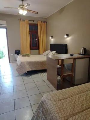 a bedroom with two beds and a desk with a table at Departamentos Centro in Villa Dolores
