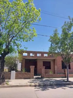 a brick building with trees in front of it at MAILY Guest House in Alta Gracia