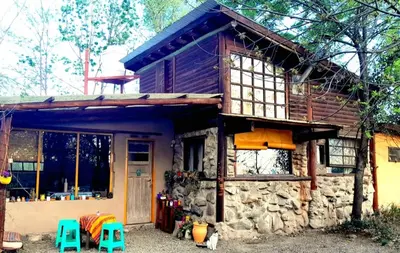 a stone house with two blue stools in front of it at Casa Sol y Luna in Villa General Belgrano