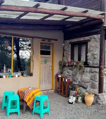 a patio with a table and two stools and a cat at Casa Sol y Luna in Villa General Belgrano