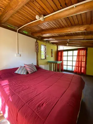 a large red bed in a room with a wooden ceiling at Casa Sol y Luna in Villa General Belgrano