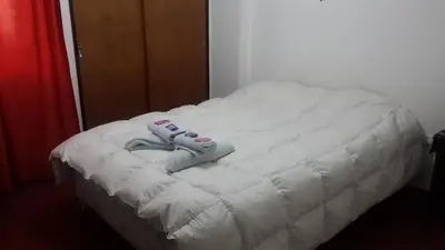 a white bed with a pair of shoes on it at Departamento Córdoba in Cordoba