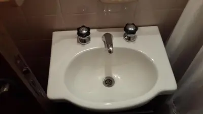 a white sink in a bathroom with two knobs at Departamento Córdoba in Cordoba