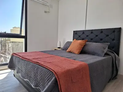 a bedroom with a bed with a red blanket on it at Gran Duplex Paseo Quattro 22 (centrico) - Cochera + Pileta in Villa Carlos Paz