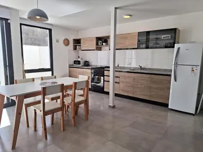 a kitchen with a table and chairs and a refrigerator at Gran Duplex Paseo Quattro 22 (centrico) - Cochera + Pileta in Villa Carlos Paz