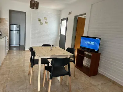 a dining room with a table with chairs and a television at CONFORTABLE Dpto. Pasaje Tucumán in Alta Gracia