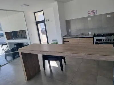 a large kitchen with a wooden table and a counter at Gran Duplex Paseo Quattro 21 (centrico) - Cochera + Pileta in Villa Carlos Paz