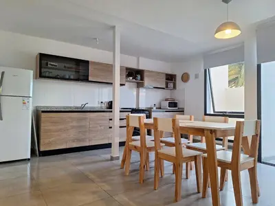 a kitchen with a table and chairs and a refrigerator at Gran Duplex Paseo Quattro 21 (centrico) - Cochera + Pileta in Villa Carlos Paz