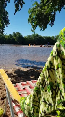 a lounge chair on a beach next to the water at Las Lavandas Tranquilidad cerca de todo in Mina Clavero