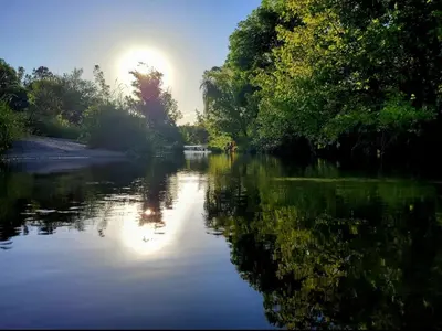 a river with the sun reflecting on the water at Amanecer serrano in Tanti