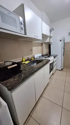 a kitchen with white cabinets and a sink and a microwave at Departamento Cofico in Cordoba