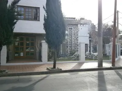 a white house with a tree in front of it at Hotel Lihuel in Villa Carlos Paz