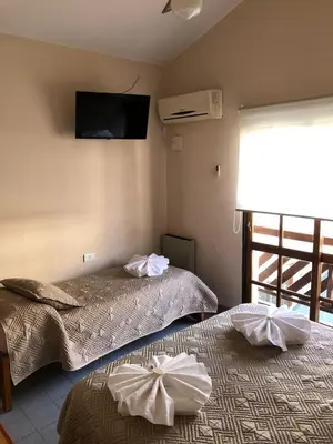 two beds in a room with a tv on the wall at Hotel Lihuel in Villa Carlos Paz