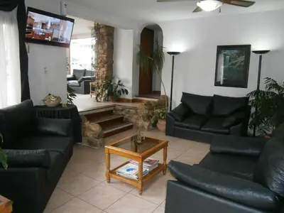 a living room with black leather couches and a table at Hotel Lihuel in Villa Carlos Paz