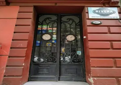 a door with clocks on it in a building at Rivera Hostel Córdoba in Cordoba