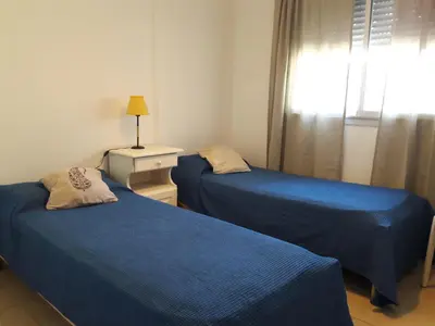 two beds in a room with blue sheets and a window at Espacio C San Juan con cochera in Cordoba