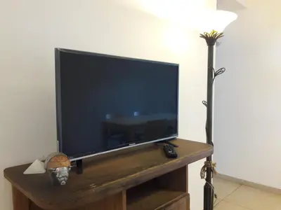 a flat screen tv sitting on a table next to a lamp at Espacio C San Juan con cochera in Cordoba