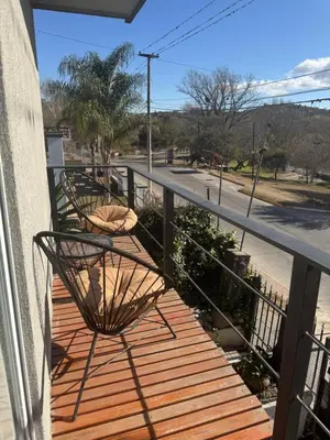 a balcony with two chairs on a wooden deck at Hermoso departamento in Villa Carlos Paz