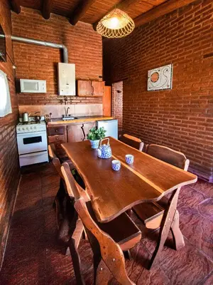 a kitchen with a wooden table and chairs in a room at Quebrada del Viento - Cabañas in Los Hornillos