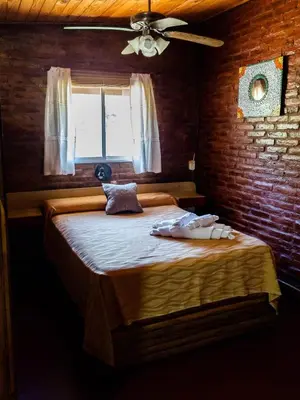 a bedroom with a large bed with a brick wall at Quebrada del Viento - Cabañas in Los Hornillos