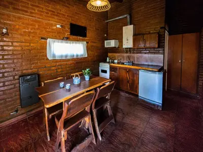 a kitchen with a wooden table and chairs in it at Quebrada del Viento - Cabañas in Los Hornillos