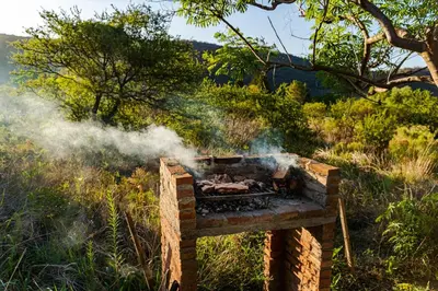 a grill with smoke coming out of it in a field at Quebrada del Viento - Cabañas in Los Hornillos