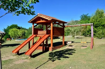 a playground with a wooden structure in a park at Quebrada del Viento - Cabañas in Los Hornillos