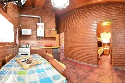a kitchen with a table and a brick wall at Quebrada del Viento - Cabañas in Los Hornillos