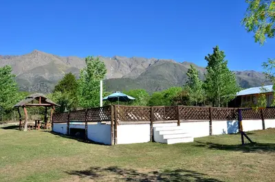 a fence with a table and an umbrella and mountains at Quebrada del Viento - Cabañas in Los Hornillos