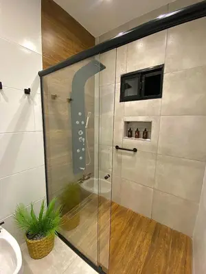 a bathroom with a shower with a television on the wall at Magnolia Suites in Nono