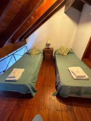 two twin beds in a attic room with wooden floors at Lirios del Campo - Chumamaya Merlo SL in Merlo