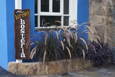 a sign in front of a blue building with plants at Lorelei in Mina Clavero