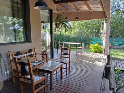 a porch with wooden chairs and a table and a table and benches at La Llilda in La Bolsa