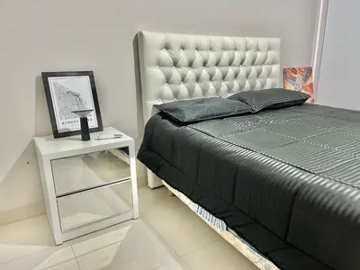 a bedroom with a bed and a white night stand at Deluxe Nueva Córdoba - Premium Balcón & Asador in Cordoba