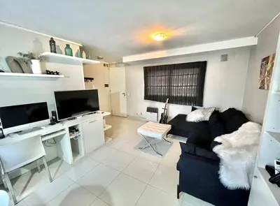 a living room with a black couch and a desk at Deluxe Nueva Córdoba - Premium Balcón & Asador in Cordoba