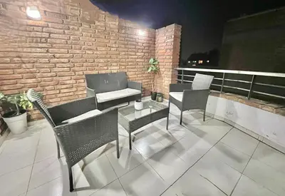 a patio with chairs and a table and a brick wall at Deluxe Nueva Córdoba - Premium Balcón & Asador in Cordoba