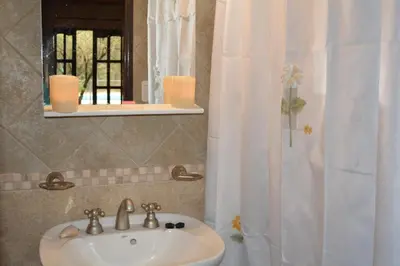 a bathroom with a sink and a mirror and a shower at Cabañas La Belen in Merlo