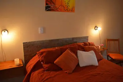 a bedroom with a bed with orange sheets and pillows at Cabañas La Belen in Merlo