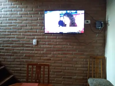 a flat screen tv hanging on a brick wall at Cabañas La Belen in Merlo