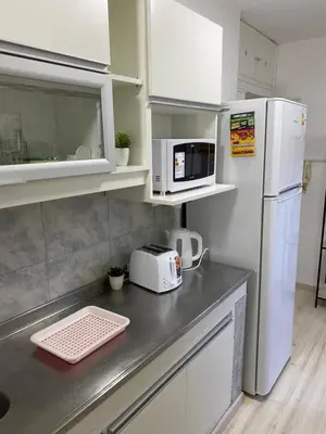 a kitchen with a counter with a microwave and a refrigerator at Departamento HOSPITAL PRIVADO - QUALITY - CORDOBA in Cordoba