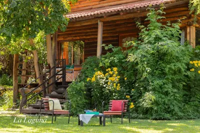 a house with three chairs and a table in front of it at La Laguna - Cabañas de Troncos in Merlo