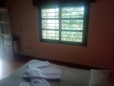 a bedroom with two towels on a bed with a window at Casa 3 Habitaciones, 2 baños pileta a compartir con el anfitrion - in Cordoba
