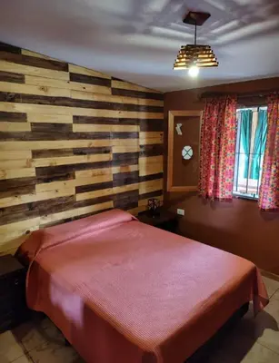 a bedroom with a wooden wall with a bed at Casa Del Arroyo in Arroyo de Los Patos